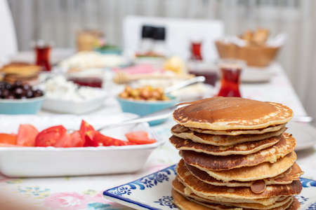 Turkish breakfast with simit, pancake, cheese, cherry tomato, cucumber, and tea on a table close up view, selective focusの写真素材