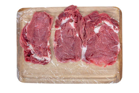 Fresh raw beef steaks   over opened vacuum packed on wooden cutting board on white background , top viewの写真素材