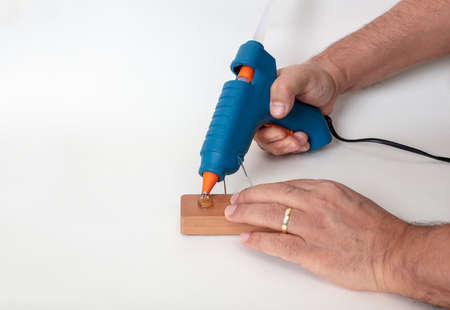 Blue glue gun in a man hand isolated on white , high angle view with shadow