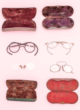 Very old eye glasses and metal cases, circa 1900-1940 on pink background top viewの写真素材