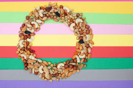 Pattern of nuts in circle form. Various nuts on colorful paper background.  Roasted chickpea, almond, hazelnut, fig, peanut, pistachio, mulberry, grape, cashew, Top view , Copy spaceの写真素材