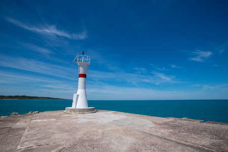 A beautiful new lighthouse on the blue sky background. Wide angle taken on a sunny summer dayの写真素材