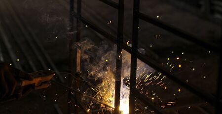 Metal welding with sparks and smoke on dark background.
