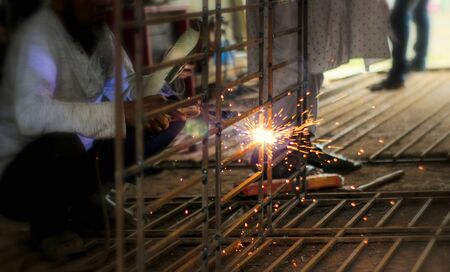 Partial view of worker welding metal with sparks at factory.Selective focus with copy space for...