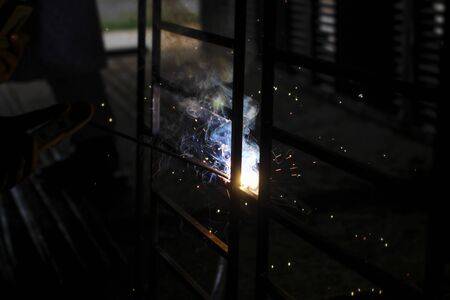 Metal welding. Sparks from electric heating. Work in the workshop. Creation of reliable fastening of materials. Fabrication of iron. The work of the master of metal.の写真素材