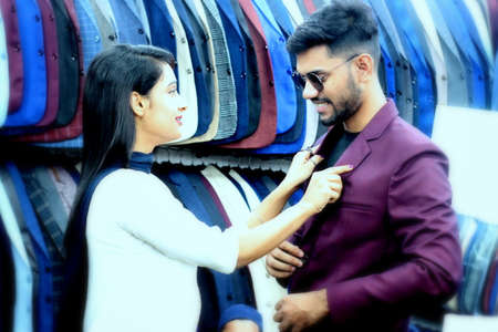 Dhaka,Bangladesh-February 23,2020 : Cute Asian boy and girl.Beautiful young lady helps her boyfriend to trail a new brand blazer in a shop.のeditorial素材