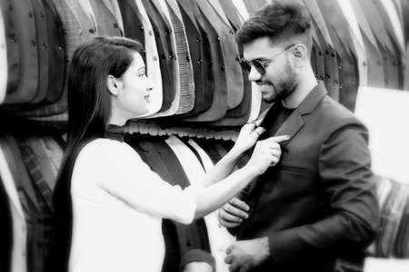 Dhaka,Bangladesh-March 19,2020 : Cute Asian boy and girl.Beautiful young lady helps her boyfriend to trail a new brand blazer in a shop.のeditorial素材