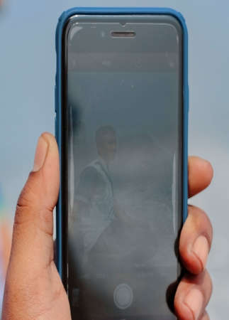 Font side of hand holding smart phone isolated on blur background .