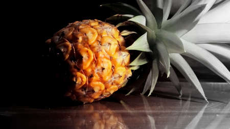 Single one full whole organic pineapple fruit on wooden background ripe fully grown mature, laid down reflect on the side.の写真素材