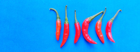 Top view of spicy red chili peppers on blue background with copy space.