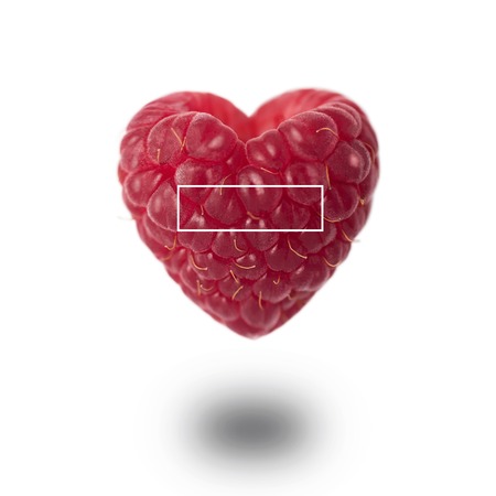 Raspberry in the shape of a heart with a shadow on a white background