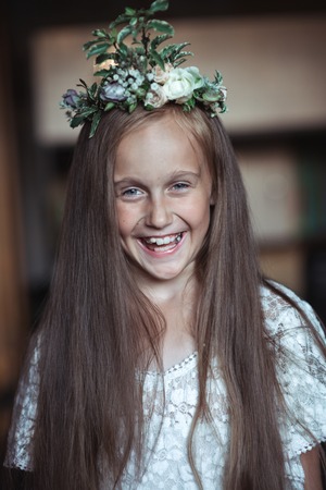 cute girl with very long hair and a beautiful wreath of flowers on her headの写真素材