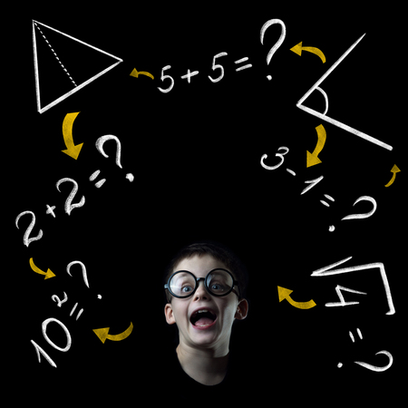 boy solve mathematics examples at the blackboard on black backgroundの写真素材