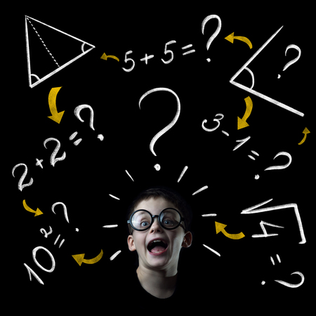 boy solve mathematics examples at the blackboard on black backgroundの写真素材