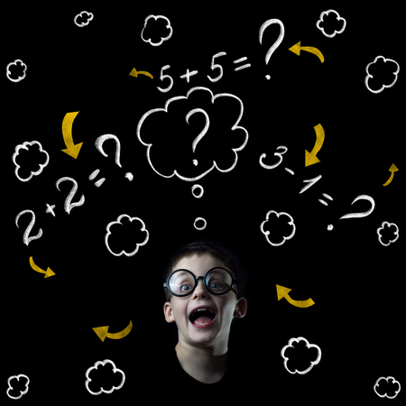 boy solve mathematics examples at the blackboard on black backgroundの写真素材