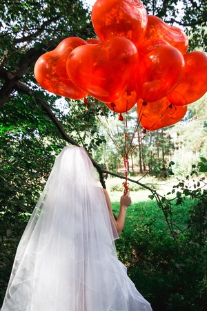 girl in white bridesmaid dress with red heart shaped ballsの写真素材