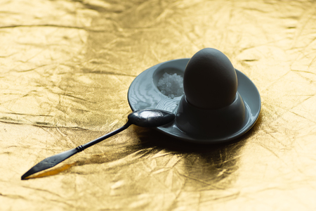 boiled egg with spoon, stand and salt on gold backgroundの写真素材