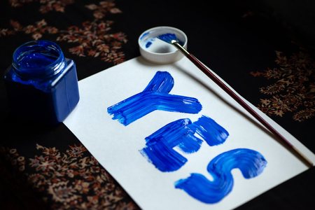 blue gouache on a white sheet says the word yesの写真素材