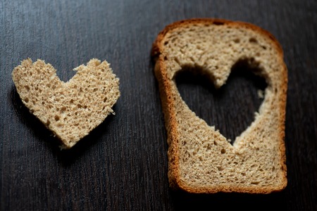 hearts carved from a piece of bread on a dark wooden tableの写真素材