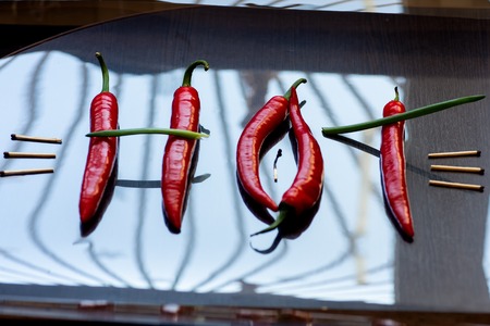 red hot pepper and onions laid out the word hot on the mirror surfaceの写真素材