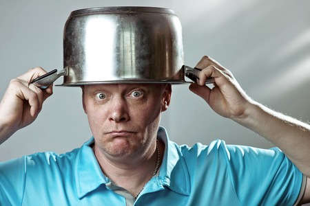 a bald brutal man in a blue t-shirt put a pot on his head