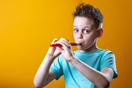 a boy in a light t-shirt playing on a pipe on a bright colored backgroundの写真素材