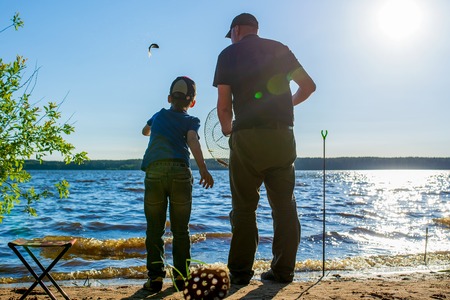 father and son on the lake fishing on a Sunny day released into the water caught fishの写真素材