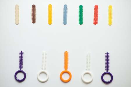 multi-colored orthodontic ligatures for alignment of the orthodontist's teeth on a light background