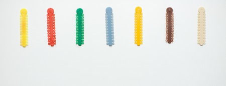 multi-colored orthodontic ligatures for alignment of the orthodontist's teeth on a light background