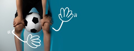 football goalkeeper with dirty knees clamped the ball between his legs on a blue backgroundの写真素材