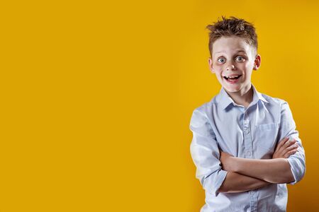 cheerful boy stands and smiles in a light shirt on a bright colored backgroundの写真素材