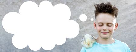 a boy in a blue t-shirt with a fluffy chicken closed his eyes and dream on a blurred background.の写真素材
