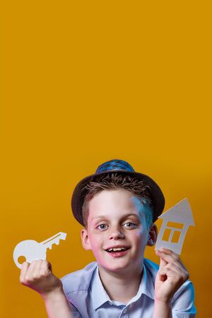 cheerful boy with a cardboard house and a key on a bright colored backgroundの写真素材
