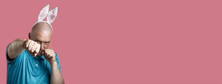 Bald brutal man in a light t-shirt and Bunny ears. Hands he strikes as in Boxingの写真素材