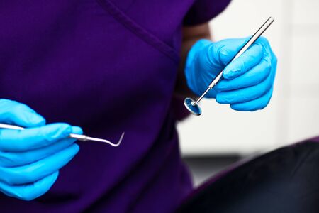 In the office of the dental clinic. The doctor holds tools for examination of teeth in blue sterile gloves.の写真素材
