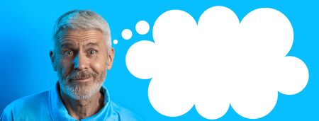 portrait of a surprised and curious gray-haired man with a beard on a blue background