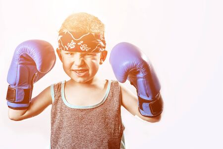 fighting emotional boy in Boxing gloves and bandana on light backgroundの写真素材