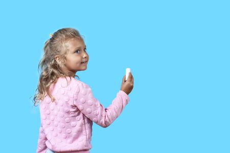 Cute girl with white chalk on blue background.