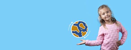 A pretty cheerful girl with dimples on her cheeks and curly hair smiles. on her hand spinning planet earth on a blue background.の写真素材