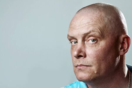 Portrait of a bald brutal man on a gray backgroundの写真素材