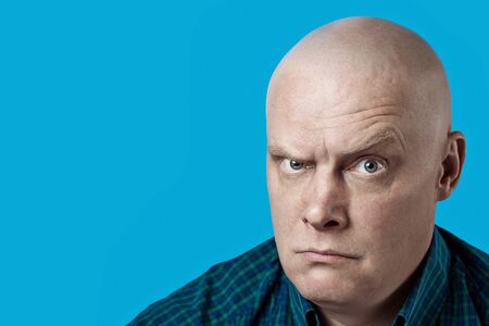 portrait of a bald brutal man in a plaid shirt on blue backgroundの写真素材