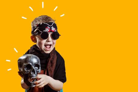 a boy rocker in black glasses, scarf, bandana and with a skull in his hands on a bright backgroundの写真素材