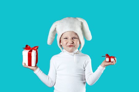 a boy dressed as a white hare tries to choose a gift on a blue background