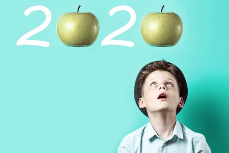 A surprised boy in a light shirt looks up. There on him falls green Apple, as a symbol of great...