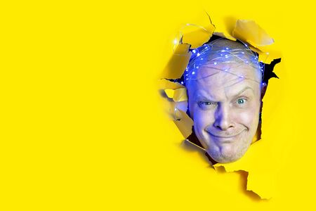 Surprised man looking through hole in yellow paper. Copy space for advertise.