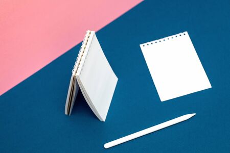 White notebook, pen and leaf on multicolored backgrounds