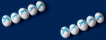 Three Easter eggs with bows on a blue background. Banner