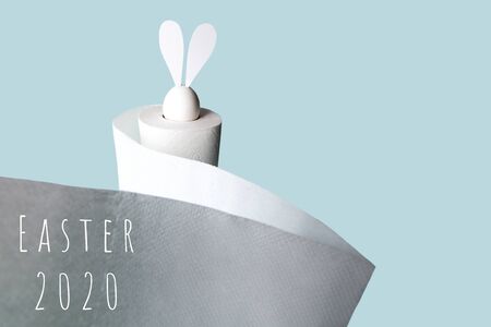 White egg with hare ears in a roll of toilet paper. Hard shadow on a light background. Concept on Easter 2020の写真素材