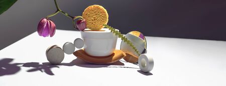 Geometric composition with orchid flower, circles of different materials and a jar of cream. The concept is on a gray background. Bannerの写真素材