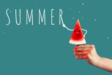 Hand holding a piece of watermelon on a stick like ice cream on greenの写真素材